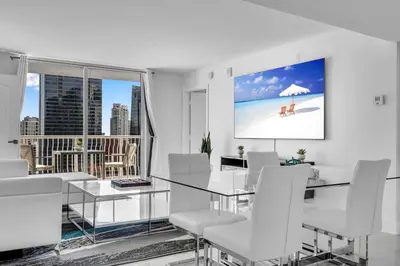 a dining room with a glass table and white chairs at Luxurious 34th floor Ocean view Private Unit in Miami