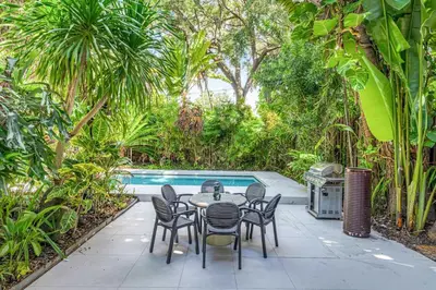 a patio with a table and chairs next to a pool at Wonderful Tropical Pool House Miami Coconut Grove in Miami