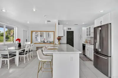 a white kitchen with a table and a refrigerator at Luxe 4BR Miami Pool-Near Airport-Games-Backyard in Miami