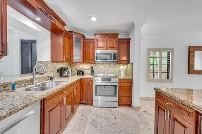 a kitchen with wooden cabinets and stainless steel appliances at Wonderful Tropical Pool House Miami South Brickell in Miami