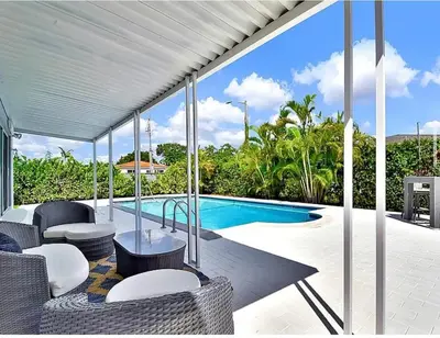 an outdoor patio with a pool and chairs and a table at Casita with pool, laundry and FREE parking in Miami
