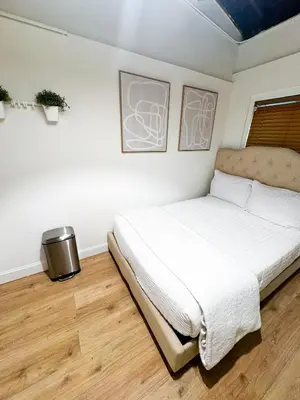a bedroom with a white bed and a wooden floor at Casita with pool, laundry and FREE parking in Miami