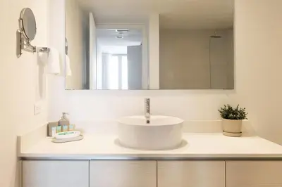 a white bathroom with a sink and a mirror at 2 Bed & 2 Bath at Beachwalk - Amazing View on 29th in Hallandale Beach