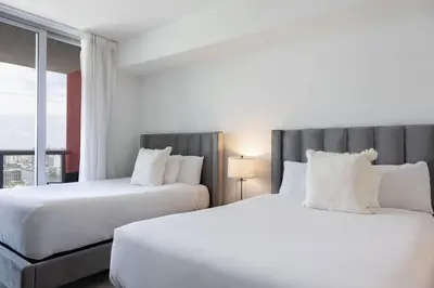 two white beds in a hotel room with a window at Epic 29th-Floor Studio at Beachwalk Resort in Hallandale Beach