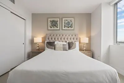 a bedroom with a large white bed with two lamps at WATERFRONT Luxury 3 Bed 3 Bath Suite in Hallandale Beach