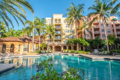 a pool at the resort with palm trees and buildings at Apartamento Aventura 3 habitaciones in Aventura