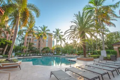 a resort pool with lounge chairs and palm trees at Apartamento Aventura 3 habitaciones in Aventura