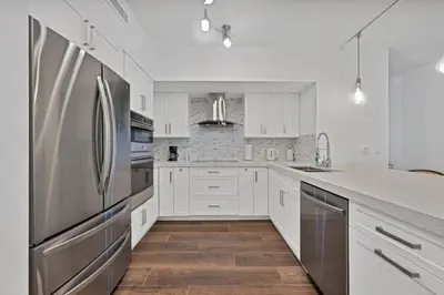 a kitchen with white cabinets and a stainless steel refrigerator at Apartamento Aventura 3 habitaciones in Aventura