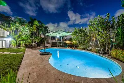 a swimming pool in the backyard of a house with an umbrella at Fort Lauderdale Water Front Oasis in Fort Lauderdale