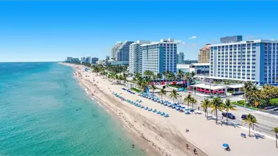 an aerial view of a beach with palm trees and buildings at Tiffany Topaz - Rooftop Pool, Gym, Walk to Beach in Fort Lauderdale