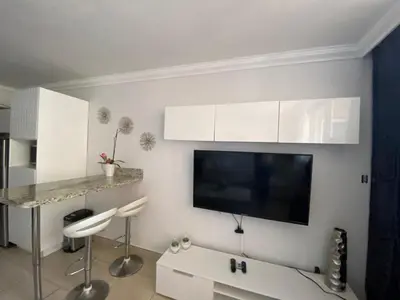 a living room with white cabinets and a flat screen tv at Lujoso Departamento Con VIstas Al Mar- Miami Beach in Sunny Isles Beach