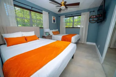 two beds in a bedroom with blue walls and windows at 3-Bedroom Tropical Villa with Heated Pool in Fort Lauderdale in Fort Lauderdale