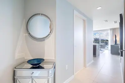 a white hallway with a mirror on a white wall at Champagne at Tiffany's - Luxury Condo by the Beach in Fort Lauderdale