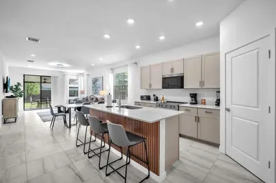 a kitchen with white cabinets and a island with bar stools at Royal Palm Gateway - Spacious Family Retreat in Sunny Homestead in Homestead