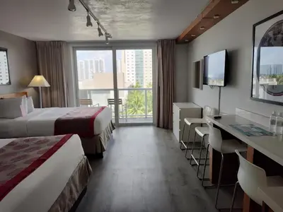 a hotel room with two beds and a balcony at Estudios en las playa de Sunny Isles Beach in Sunny Isles Beach