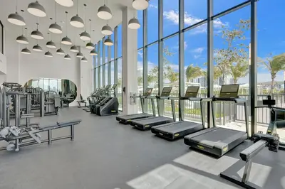 a gym with rows of tread machines and windows at New 1Bed 1 bath Ocean view in Miami Beach