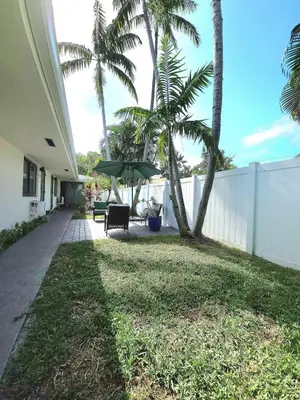 a yard with palm trees and a white fence at Aquamarina in Fort Lauderdale