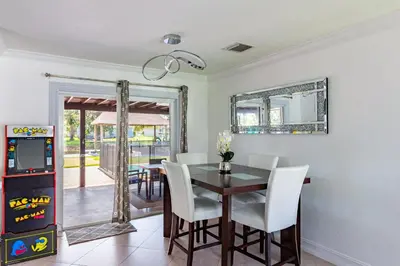 a dining room with a table and a video game at Waterfront 3BR with Pool Tiki Hut & Mini Golf in Miami Gardens