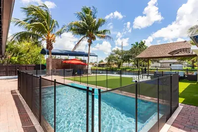 a swimming pool with aicrobialicrobialicrobialicrobialicrobial fencing around a swimming pool at Waterfront 3BR with Pool Tiki Hut & Mini Golf in Miami Gardens
