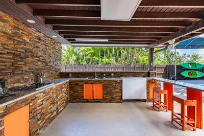 an outdoor kitchen with orange cabinets and a brick wall at Waterfront 3BR with Pool Tiki Hut & Mini Golf in Miami Gardens