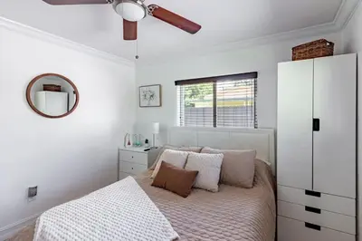 a white bedroom with a bed and a mirror at Waterfront 3BR with Pool Tiki Hut & Mini Golf in Miami Gardens