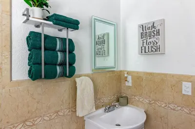 a bathroom with a sink and a toilet and a mirror at Waterfront 3BR with Pool Tiki Hut & Mini Golf in Miami Gardens