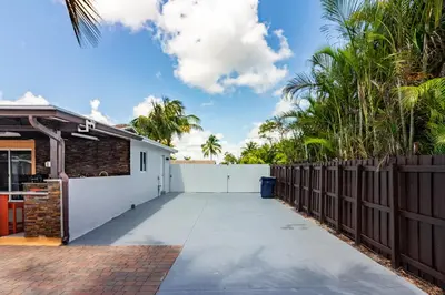 a driveway in front of a house with a fence at Waterfront 3BR with Pool Tiki Hut & Mini Golf in Miami Gardens