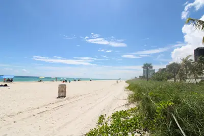 a sandy beach with people on it and the ocean at Oceanview Studio at Castle Beach Club – Pool, Beach Access, Valet Parking, Gym & More! in Miami Beach