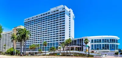 a large building with palm trees in front of it at Oceanview Studio at Castle Beach Club – Pool, Beach Access, Valet Parking, Gym & More! in Miami Beach