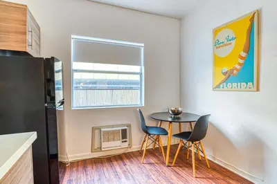 a small kitchen with a table and chairs and a window at So South Beach in Miami Beach