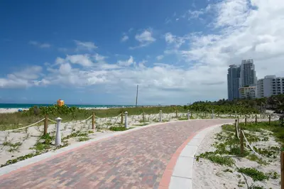 a brick road leading to the beach with a city at So South Beach in Miami Beach