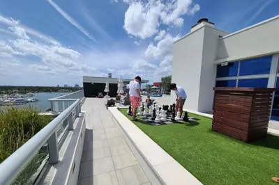 a group of men playing chess on the balcony of a house at New Luxury Beachfront Condo with Rooftop Pool in Hollywood