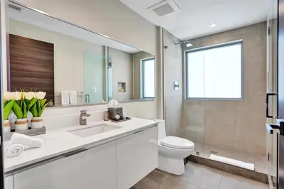 a bathroom with a sink and a toilet and a mirror at New Luxury Beachfront Condo with Rooftop Pool in Hollywood