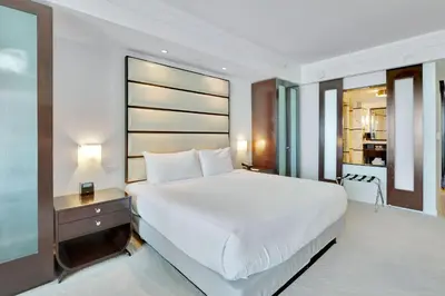 a bedroom with a large white bed and a kitchen at Luxury Oceanview Suite at the Fontainebleau Miami Beach with Balcony, King & Sofa Bed in Miami Beach