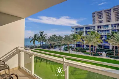 a balcony with a view of the ocean and palm trees at Spectacular 1-Bedroom Sea View Luxury & Comfort in Miami Beach