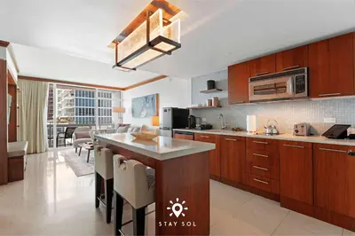 a kitchen with wooden cabinets and a dining room at Spectacular 1-Bedroom Apartment Beach view in Miami Beach