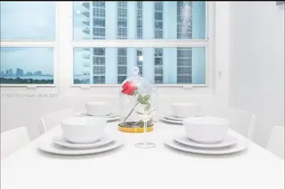 a white table with a vase with a rose in it at UNIT #908 Castle Beach Club Condominium in Miami Beach