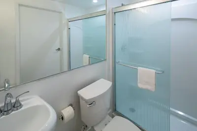 a bathroom with a toilet and a glass shower at President Hotel Villa in Miami Beach