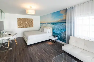 a bedroom with a bed and a desk and a couch at President Hotel Villa in Miami Beach