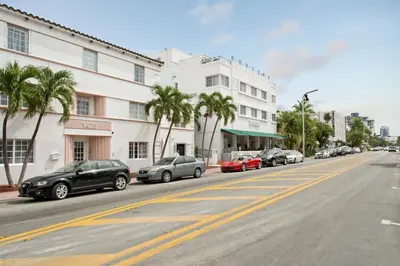 a row of cars parked on a street next to a building at President Hotel Villa in Miami Beach