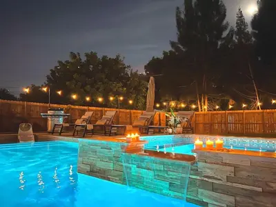 a swimming pool with lights in a backyard at night at Fox Garden Luxury Boho Near Downtown & Beach home in Fort Lauderdale