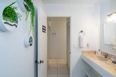 a white bathroom with a sink and a mirror at Fox Island Heated Spa- Downtown & Beach home in Fort Lauderdale