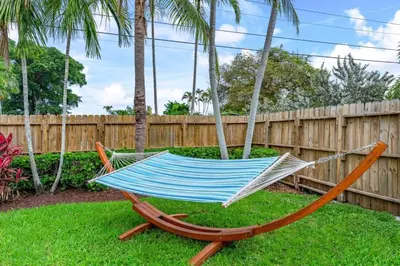 a hammock in a yard next to a fence at Fox Island Heated Spa- Downtown & Beach home in Fort Lauderdale