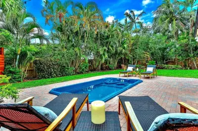 a backyard with a swimming pool and patio furniture and trees at Fox Island Heated Spa- Downtown & Beach home in Fort Lauderdale