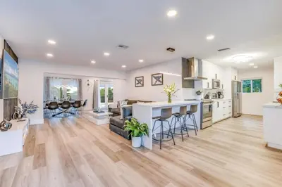an open kitchen and living room with white walls and wooden floors at Fox Private Resort- Near Downtown & Beach home in Fort Lauderdale