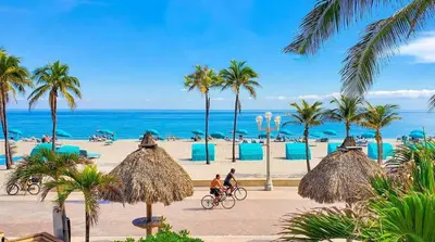 two people riding bikes on a beach with palm trees at Designer 2br, king-size bed, 5mins to the beach J1 in Hollywood