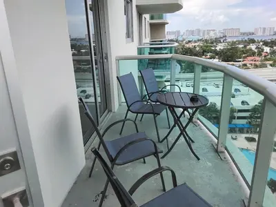 a balcony with chairs and a table and a view of the pool at Ocean reserve 2 bedroom plus den in Sunny Isles Beach