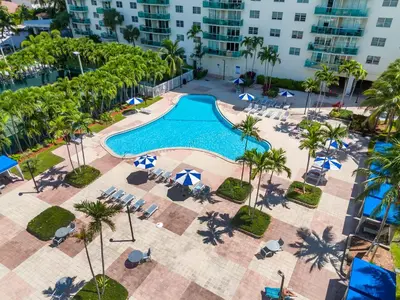 an overhead view of a swimming pool with chairs and umbrellas at Resort at Sunny Isles Beach with Ocean view in Sunny Isles Beach