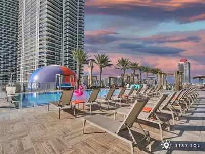 a row of lounge chairs next to a swimming pool at Stunning 1BR Apt With Ocean View Balcony in Hollywood