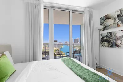 a bedroom with a bed and a view of a balcony at Coastal Retreat Modern Studio w Harbour Views in Hallandale Beach